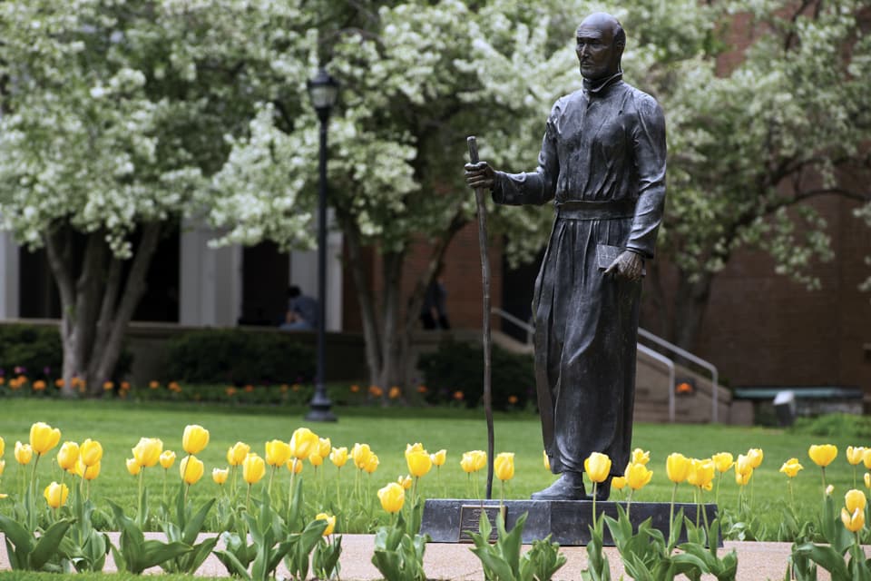 The statue of St. Ignatius on SLU's quad surrounded by tulips