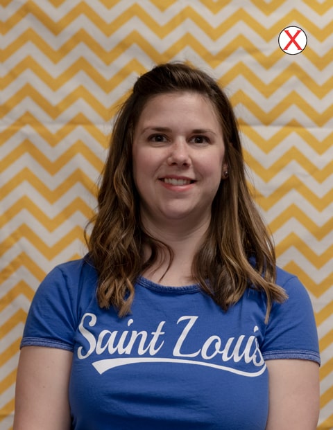 Example of bad background A headshot of a woman wearing a SLU t-shirt. The background of the photo is a yellow-and-white zigzag striped curtain.