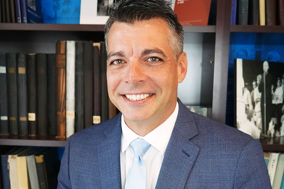 A headshot photo of Tony Minor in front of a bookcase.