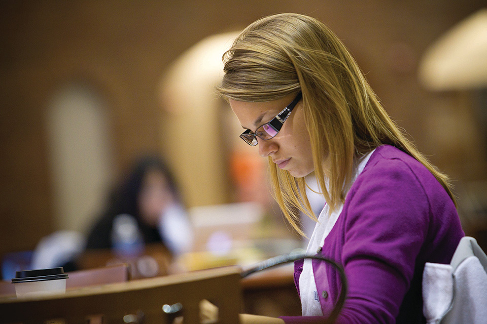 Richard A. Chaifetz School of Business Student Business Student looks down at a table while working with a cup of coffee.