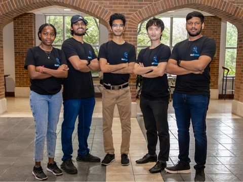 Five members of the med reveal team stand in a row with their arms folded, wearing matching t-shirts.