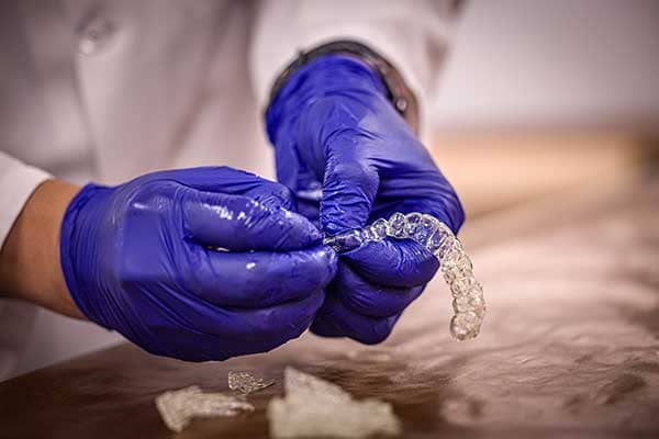A close-up of a pair of orthodontic aligners. The aligners are clear plastic trays that fit over a set of teeth.