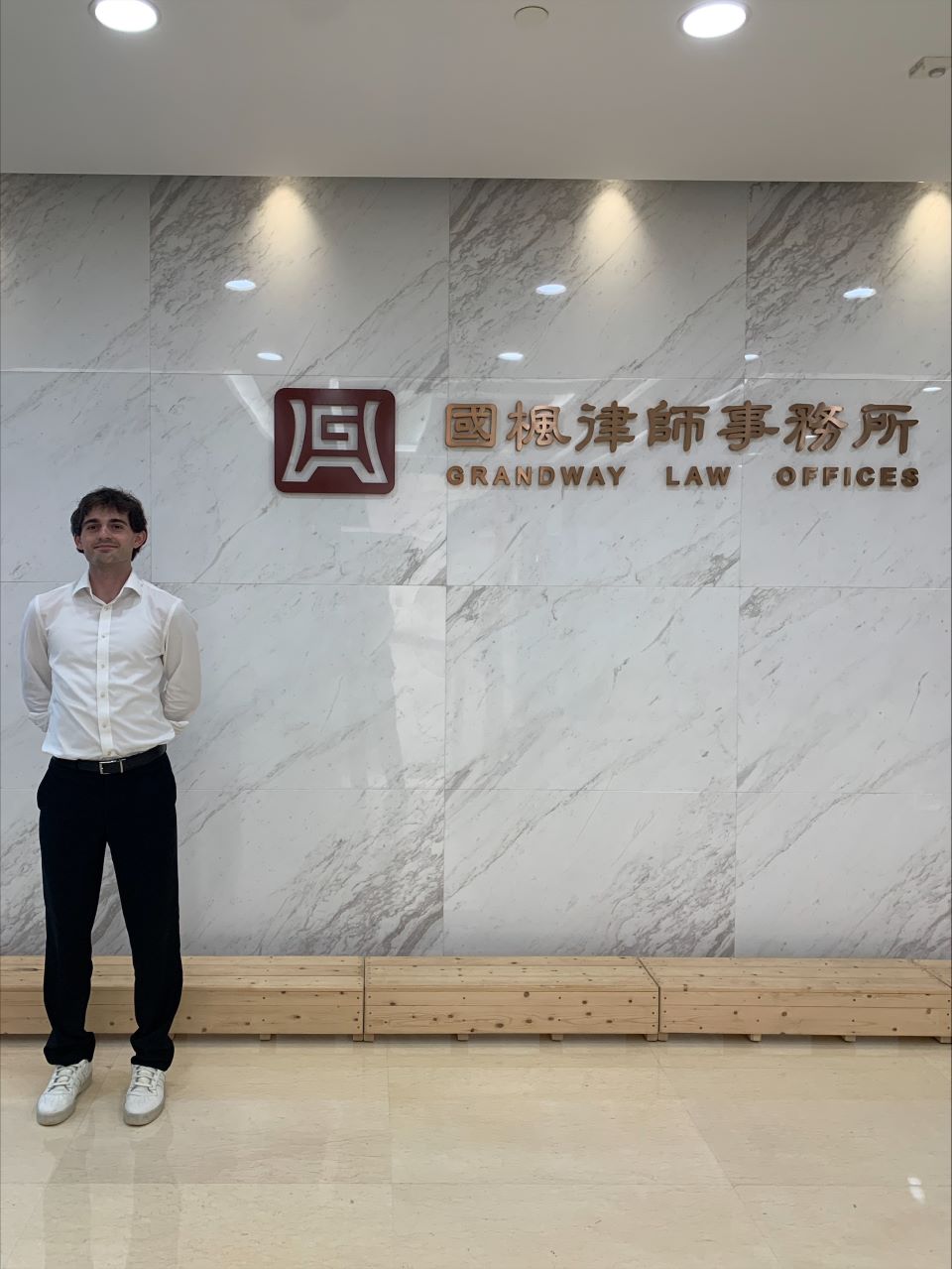 Justin Fuller poses at the entrance of the firm in Shanghai were he worked over the summer
