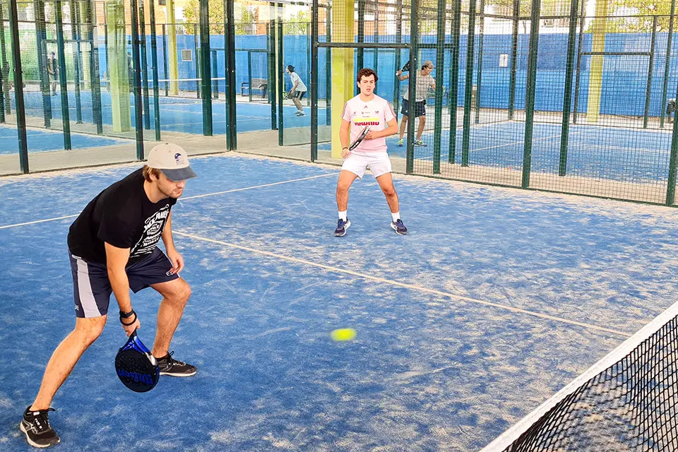 Three students play soccer on a field outside.