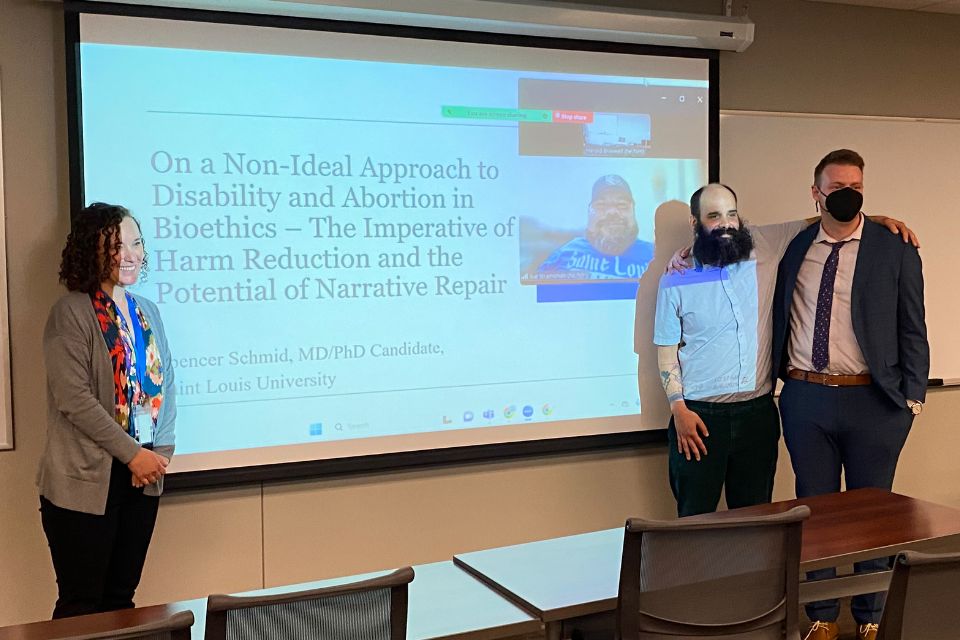 A group poses in front of projector