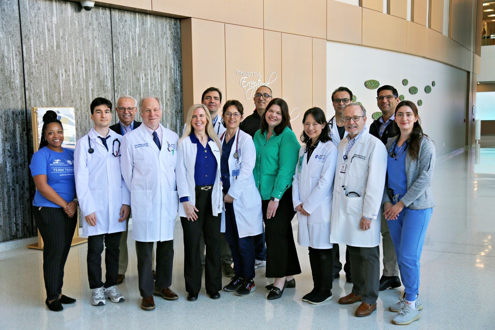 Department faculty pose for a group photo in the hallway of a SLU School of Medicine building.