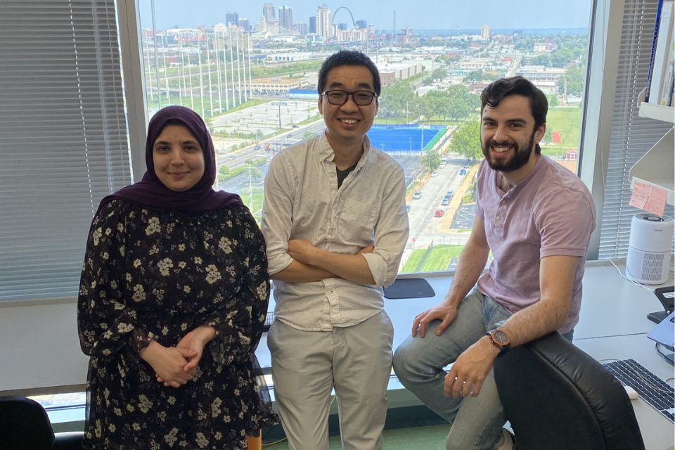 Researchers stand in front of a lab window with a view of the St. Louis skyline. 