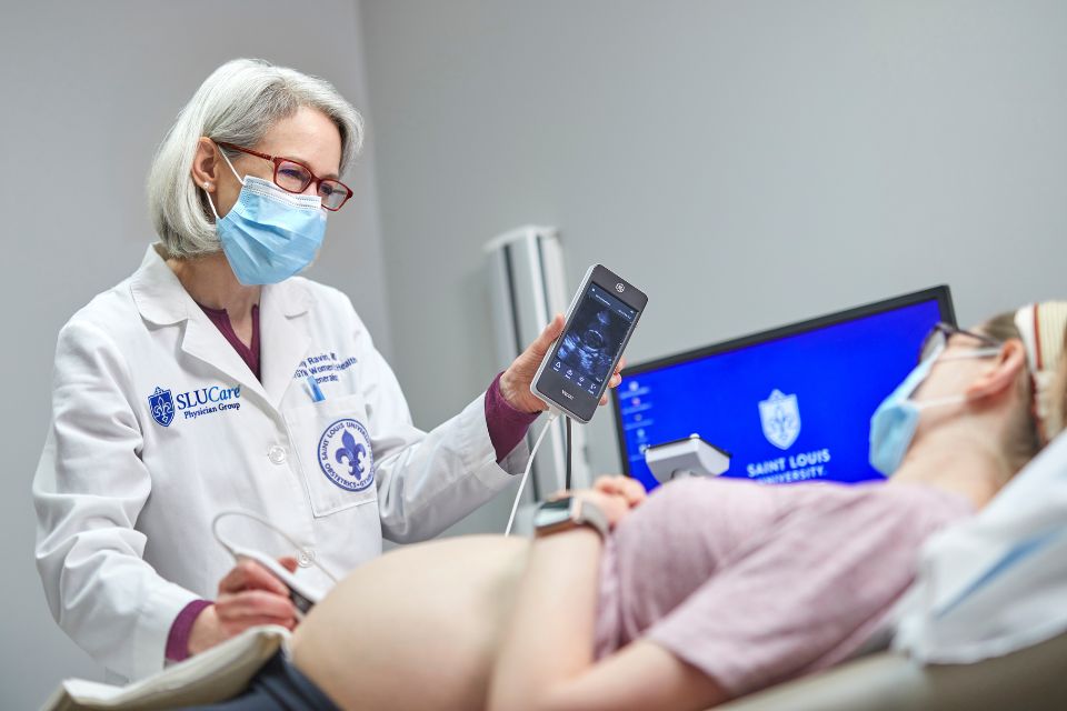 A doctor shows an ultrasound image of a fetus to a pregnant woman.