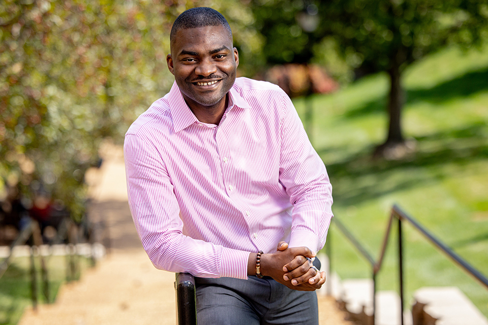 Olu Owoeye, Ph.D., leans against a rail for a photo shot outdoors during the day. 