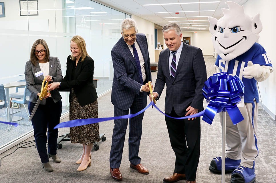 The College for Public Health and Social Justice celebrated their new space in the Wool Ceremony with a ribbon-cutting ceremony on Monday, March 31. From left are CPHSJ Dean Leslie McClure, Ph.D.; Interim Vice President of Research Ellen Barnidge, Ph.D.; SLU President Fred P. Pestello, Ph.D.; Provost Mike Lewis, Ph.D.; and the Billiken. 