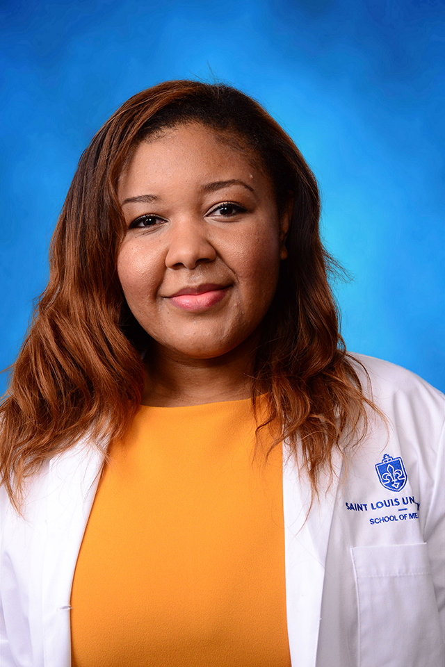 Alexis Cole poses for a headshot in her white coat against a blue background.