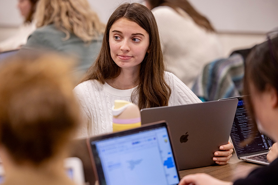 Michael Rozier, S.J. Ph.D., stands in front of a chalkboard speaking to a room full of students about the topic of justice. 