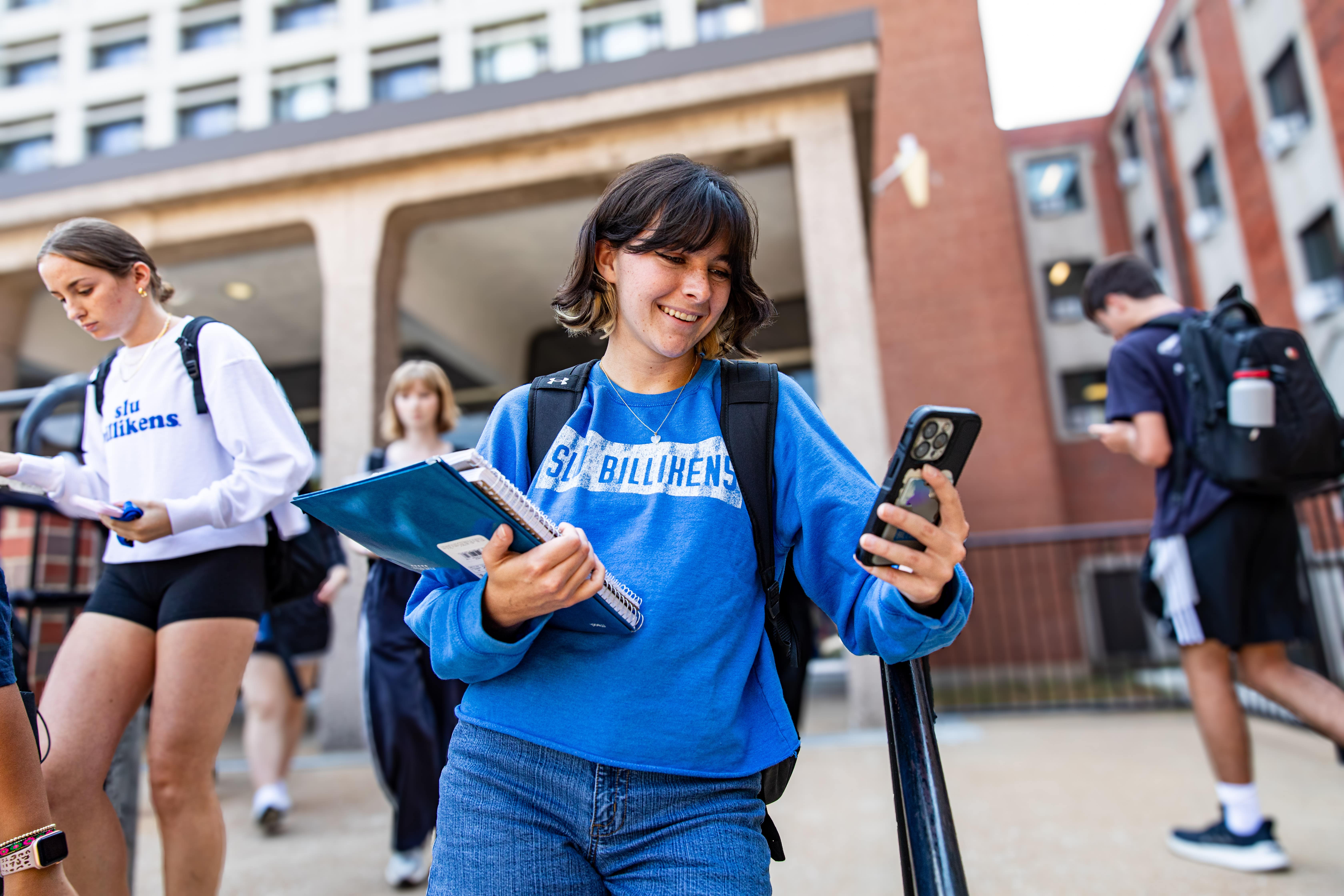 Five students jumping in mid-air in front of colorful SLU mural